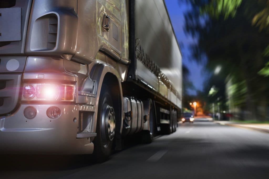 a truck driving down a street at night